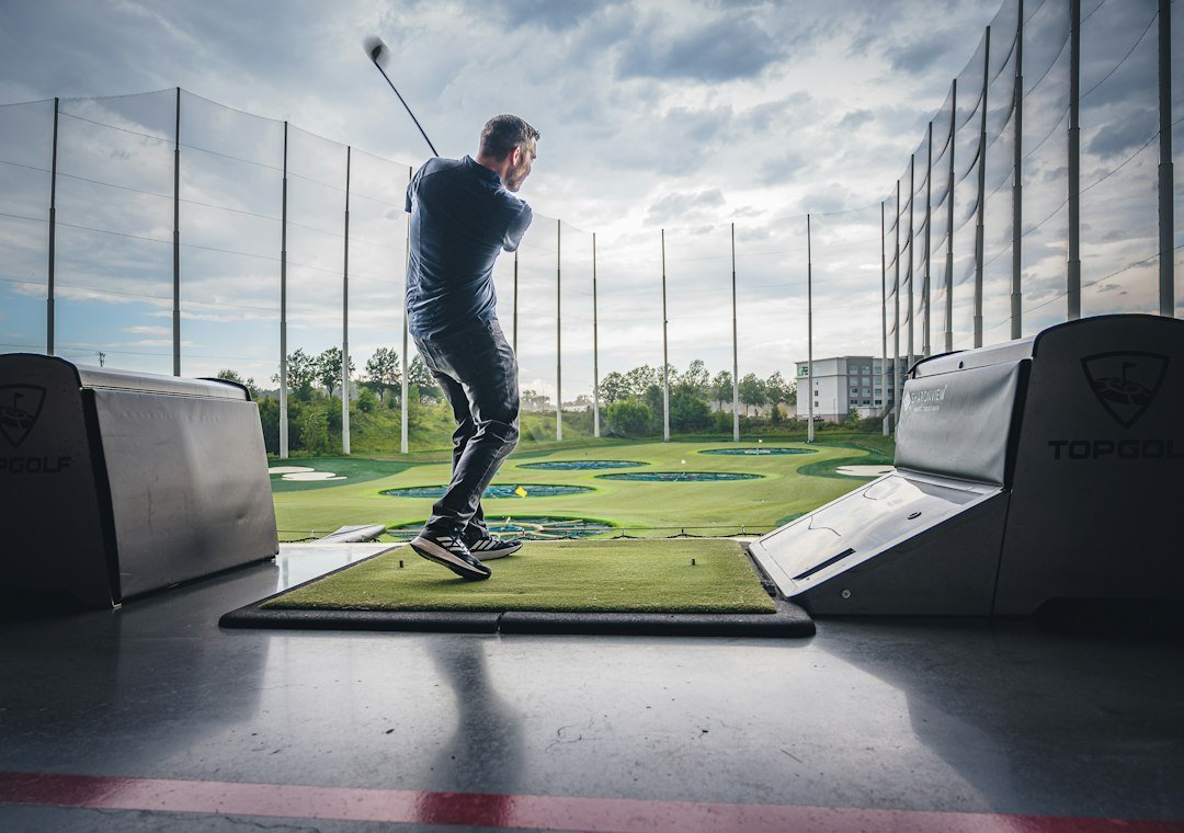 Golfer practising from a hitting mat at a driving range.