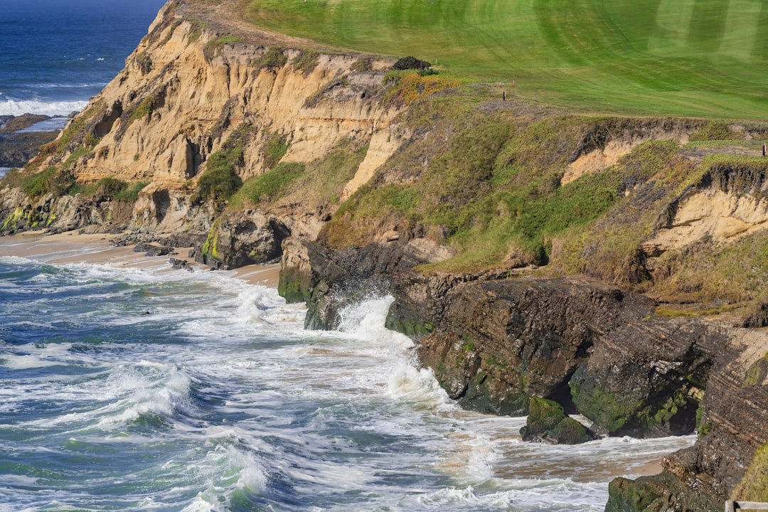 Coastal golf fairway set above rocky ocean cliffs.