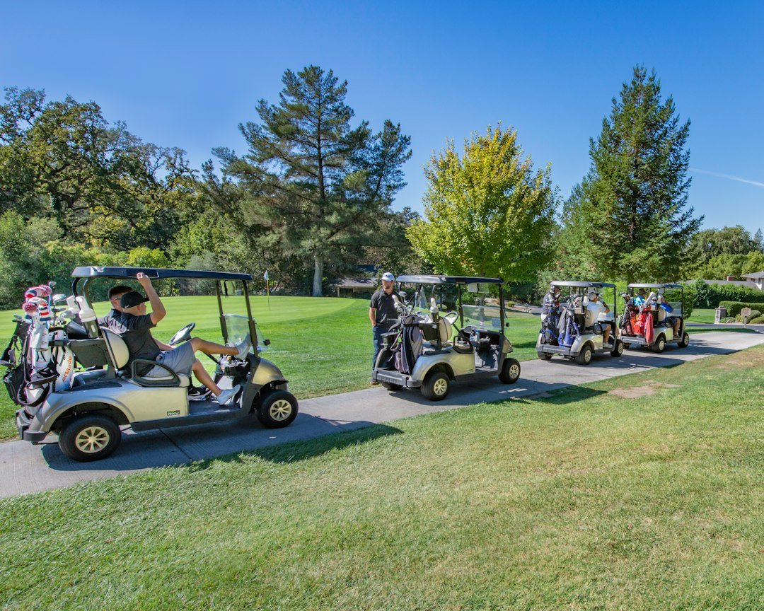 white golf cart on green grass field during daytime